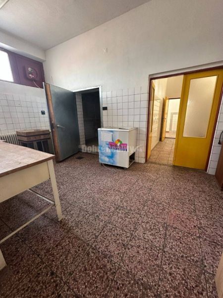 Dobré reality - Polyfunkčný objekt na predaj - Interiér budovy s dlažbou, stenami obloženými kachličkami a dreveným stolom.