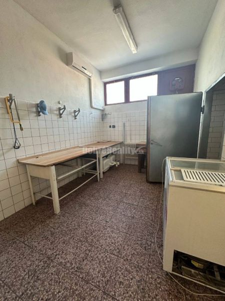 Dobré reality - Polyfunkčný objekt na predaj - Miestnosť v budove s dlažbou, pracovným stolom a chladničkou.