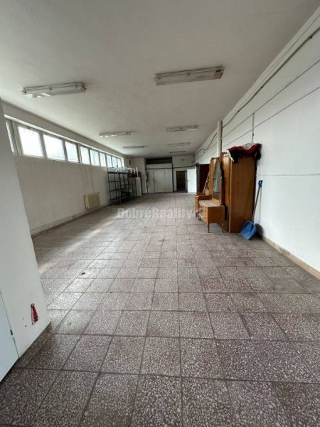 Dobré reality - Polyfunkčný objekt na predaj - Interiér budovy s dlažbou a svetlíkmi, priestranná hala so skladovacími regálmi.