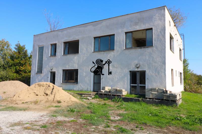 Na predaj sklady v obci Chrastince, Veľký Krtíš - Dvojposchodová budova s oknami, hlinou a zeleňou na ulici Chrastince.