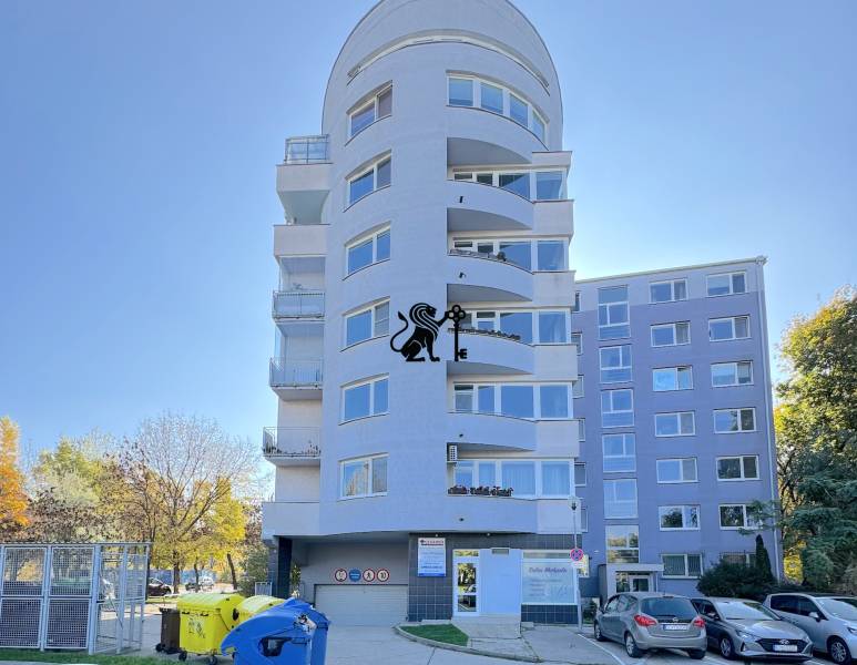 Postúpenie zabehnutej zdravotníckej prevádzky - Tomašíkova ul., BA II - Päťposchodový bytový dom s balkónmi a stromami v pozadí na slnečnej ulici.