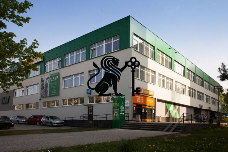 Prenájom kancelárskeho priestoru v komplexe AB Hliny - Na ulici Hliny je budova so službami kancelárie obklopená stromami a parkujúcimi autami.