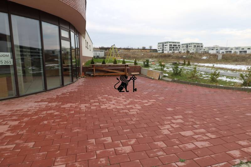 Predaj OP o výmere 86,62 m2 na predaj, Senec - Na ulici Vtáčia: prázdne obchodné priestory so sklenenými dverami a vonkajšou terasou.