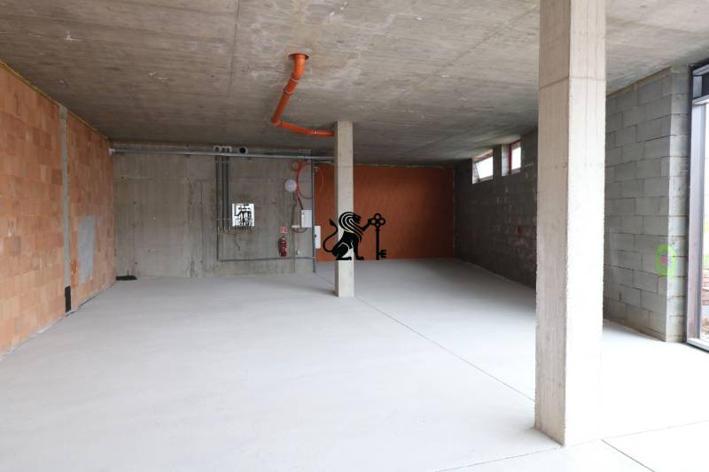 Predaj OP o výmere 86,62 m2 na predaj, Senec - Prázdne obchodné priestory so surovými stenami a potrubím na ulici Vtáčia.