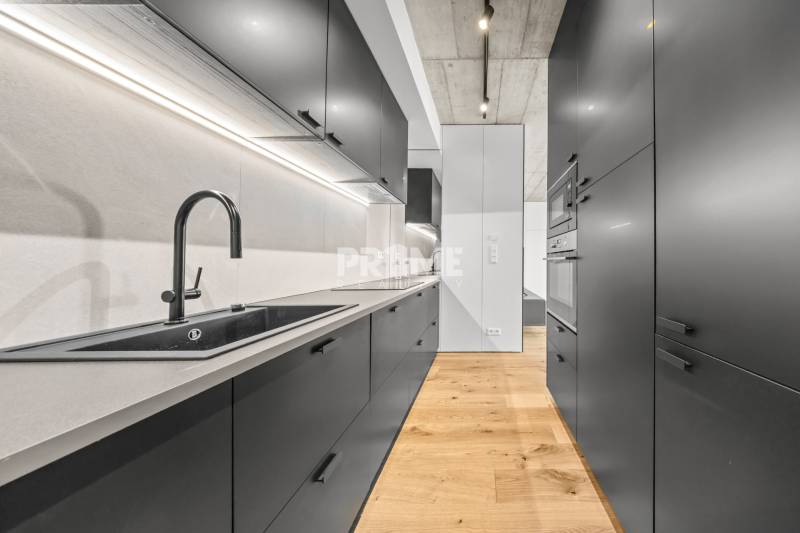 EXKLUZÍVNY MEZONETOVÝ 4i byt ( 103 m2 ), NADSTAVBA, KLÍMA, LOGGIA,NIVY - Kuchyňa v 4-izbovom byte na ulici Páričkova s drevenou podlahou a čiernym vybavením.