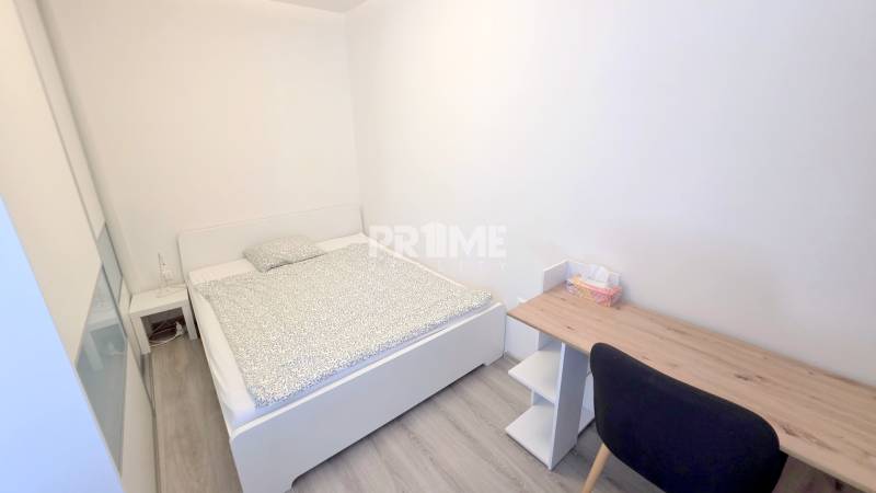 PEKNÝ 1,5i byt, CENTRUM, BALKÓN, PARKING, Kozia ulica, Staré Mesto - Spálňa v 1-izbovom byte s posteľou, stolíkom a podlahou s dreveným dekorom.