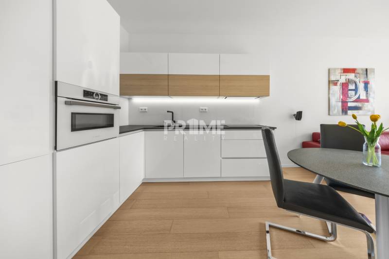 EXKLUZÍVNY 2i byt (16 p.),SKY PARK, KLÍMA, VÝHĽAD, PARKING, VEŽA I - Kuchyňa v 2-izbovom byte s bielymi skrinkami, stolom a červeným gaučom.