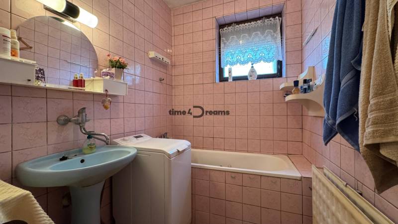 NA PREDAJ rodinný dom v Jelšovciach - EXKLUZÍVNE - Kúpeľňa s modrým umývadlom, práčkou a vaňou v rodinnom dome, ružové kachličky.