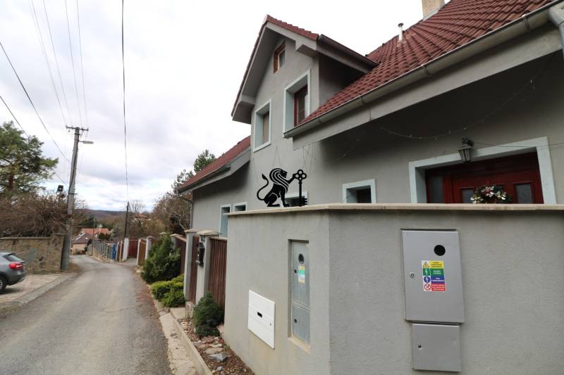 ZNÍŽENÁ cena-viacgeneračný  rodinný dom v Borinke - Rodinný dom pri ulici na Borinke s červenou strechou a okrasným levom.