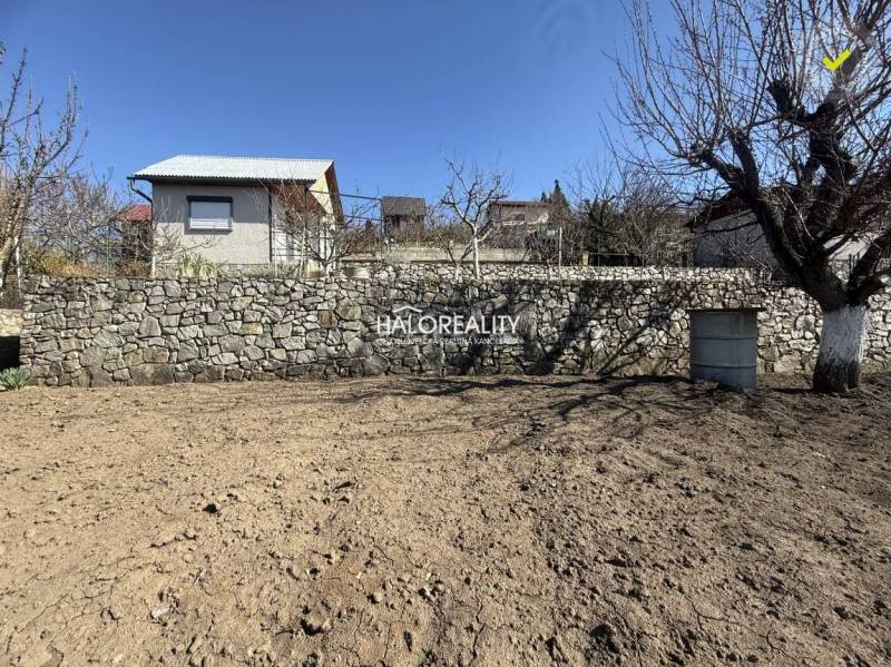 Predaj, záhradná chata Brodzany, pozemok 700 m2 - EX... - Drevená chata za kamenným múrom, obklopená stromami, v pokojnej časti záhrady.
