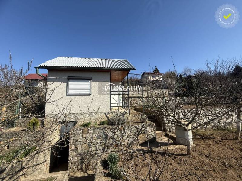 Predaj, záhradná chata Brodzany, pozemok 700 m2 - EX... - Záhrada s menším domčekom, kamennými schodmi, ovocnými stromami pod modrou oblohou.