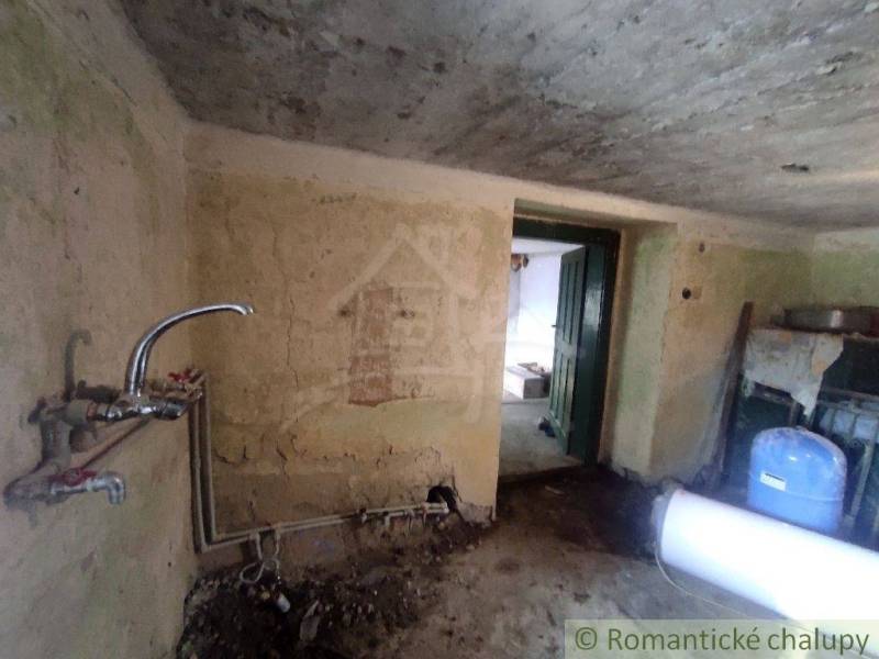 NOVÁ NIŽŠIA CENA ! Priestranný rodinný dom v pôvodnom stave v malej de - Miestnosť v rodinnom dome s umývadlom a otvorenými dverami.