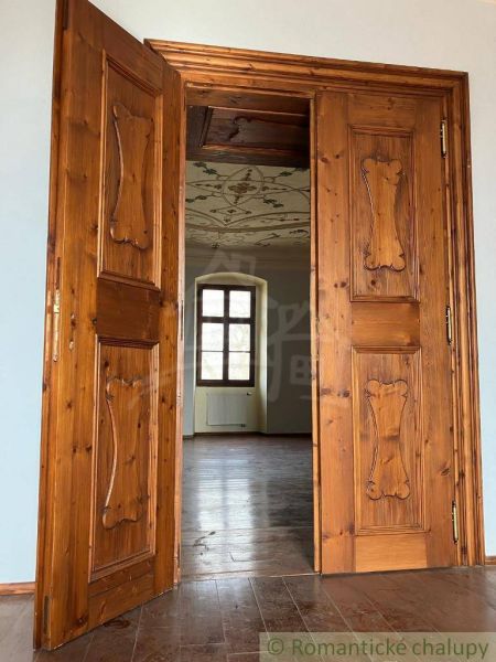Rekonštruovaný barokový kaštieľ s kaplnkou a rozsiahlym parkom v Trávn - Drevené dvere vedú do miestnosti s podlahou s dreveným dekorom a zdobeným stropom.