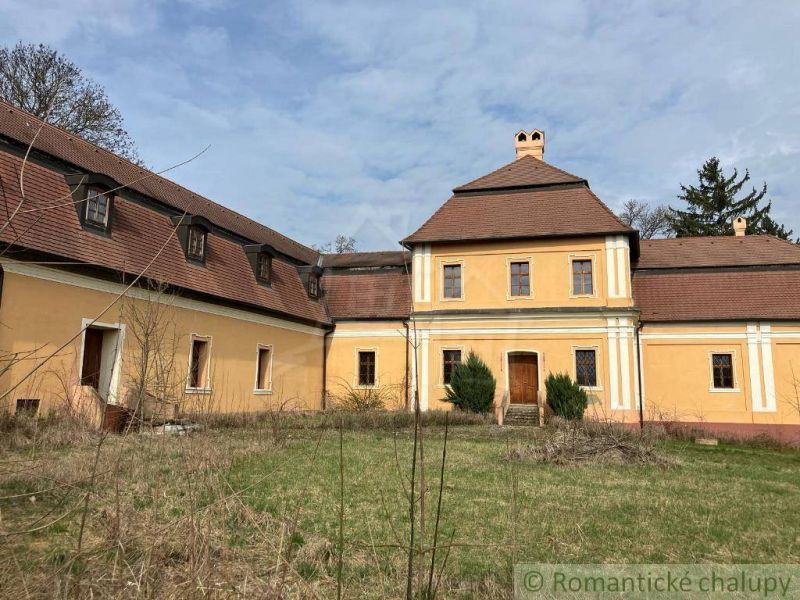 Rekonštruovaný barokový kaštieľ s kaplnkou a rozsiahlym parkom v Trávn - Historická žltá budova v Trávnici so šikmou strechou, obklopená záhradou. Zvláštne nehnuteľnosti.