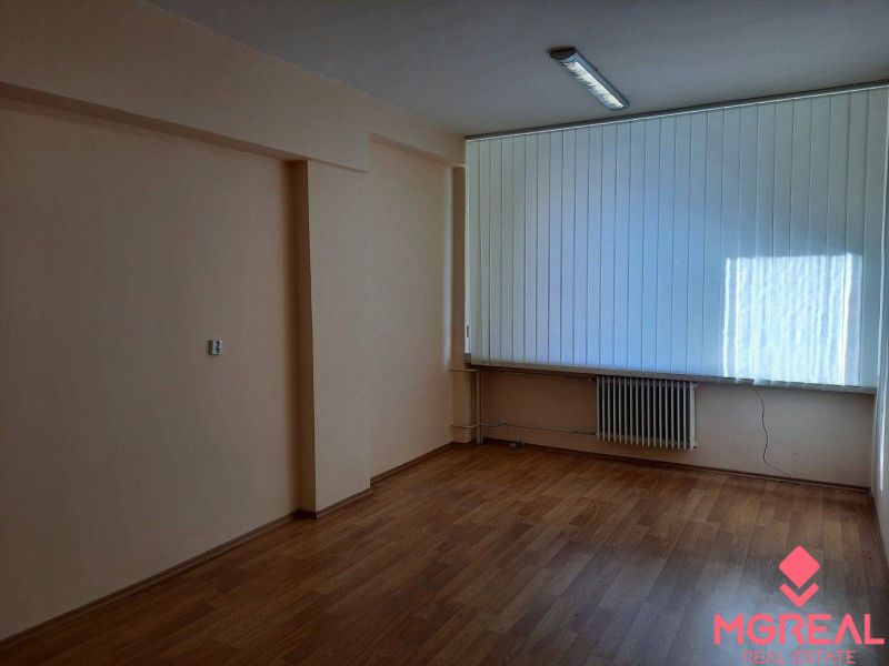 Prenájom kancelárií 21 m2 v centre Trnavy - Prázdne kancelárie s podlahou s dreveným dekorom a veľkými vertikálnymi žalúziami.