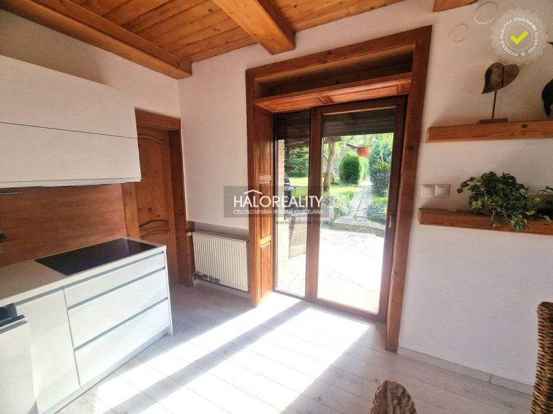 Predaj, rodinný dom Prievidza - Kuchyňa v rodinnom dome s podlahou s dreveným dekorom a výhľadom do záhrady.
