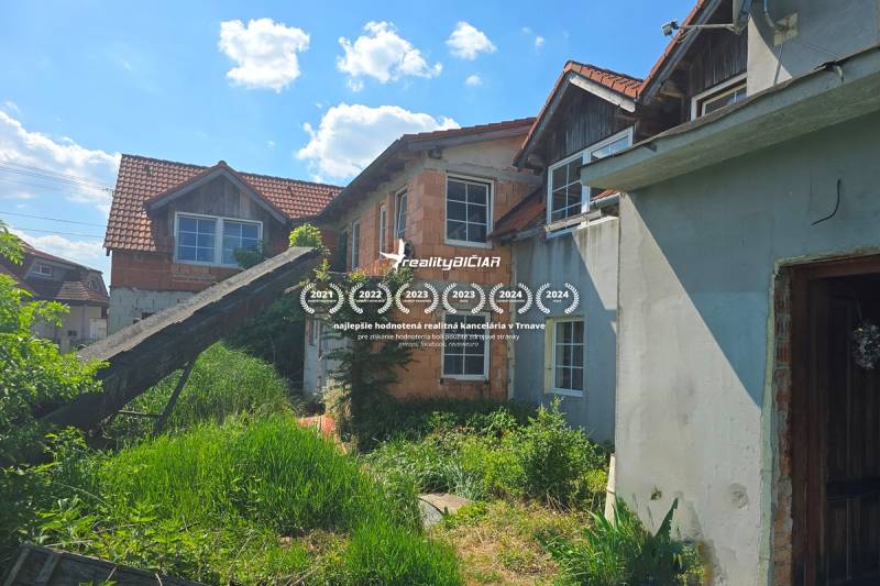 NOVÁ CENA - investičná príležitosť v obci Bíňovce - Rodinný dom v Bíňovciach na Bíňovciach s nedokončenou fasádou a bujnou vegetáciou v záhrade.