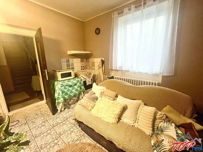 Rodinný dom s veľkým pozemkom - Turňa nad Bodvou - Interiér rodinného domu s pohovkou, mikrovlnkou a schodiskom v pozadí.