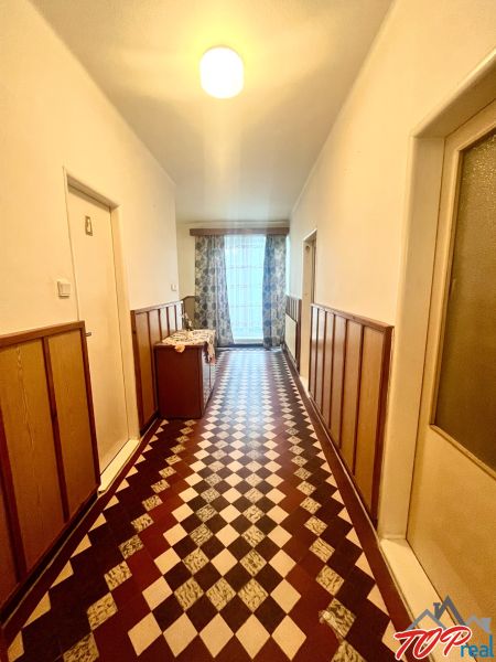 Rodinný dom s veľkým pozemkom - Turňa nad Bodvou - Chodba v rodinnom dome s výraznou geometrickou dlažbou a záclonami na okne.