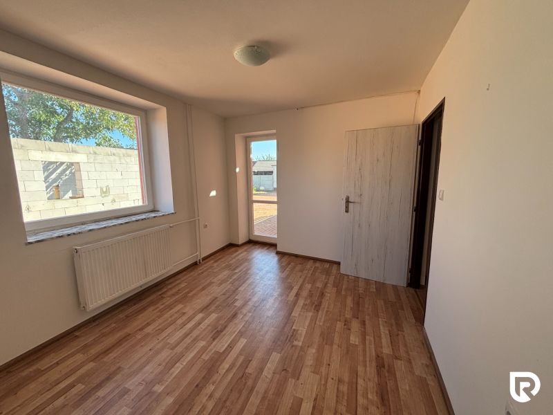 6-izbový rodinný dom s pozemkom 2218m2  | Horňany - Izba s podlahou s dreveným dekorom v rodinnom dome, vonkajší výhľad.