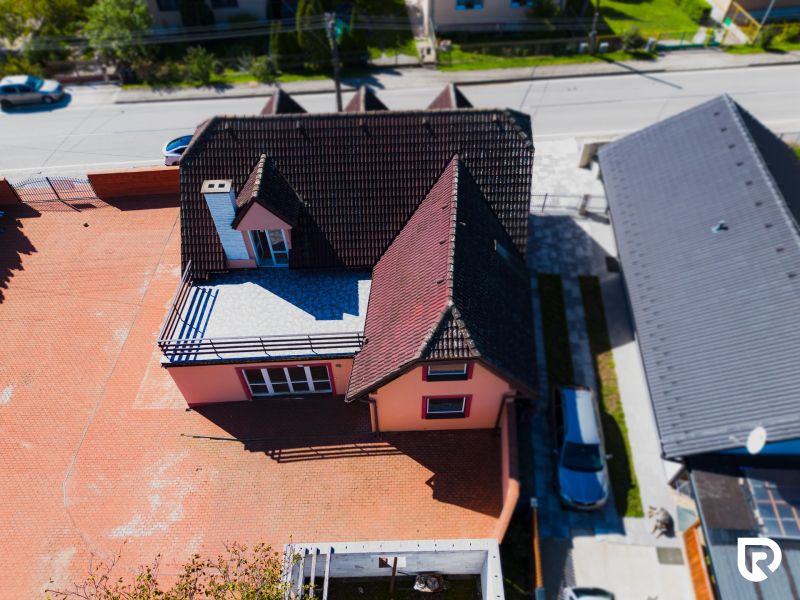 6-izbový rodinný dom s pozemkom 2218m2  | Horňany - Rodinný dom v Horňanoch s červenou strechou a veľkým spevneným dvorom.