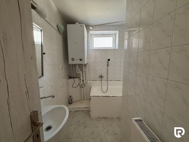 6-izbový rodinný dom s pozemkom 2218m2  | Horňany - Kúpeľňa v rodinnom dome s vaňou, bielymi obkladačkami a vykurovacím kotlom.