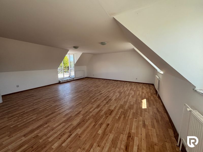 6-izbový rodinný dom s pozemkom 2218m2  | Horňany - Podkrovná izba v rodinnom dome s podlahou s dreveným dekorom, priestranné okno na terasu.