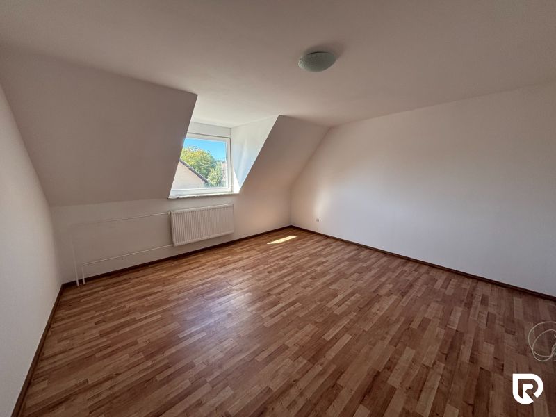 6-izbový rodinný dom s pozemkom 2218m2  | Horňany - Podkrovná izba v rodinnom dome s podlahou s dreveným dekorom a strešným oknom.