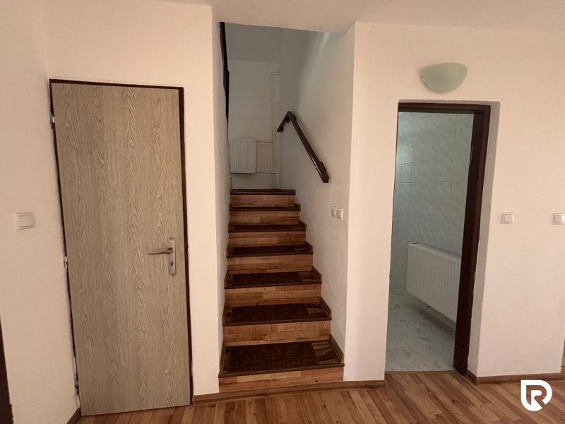 6-izbový rodinný dom s pozemkom 2218m2  | Horňany - Chodba v rodinnom dome so schodiskom a podlahou s dreveným dekorom.