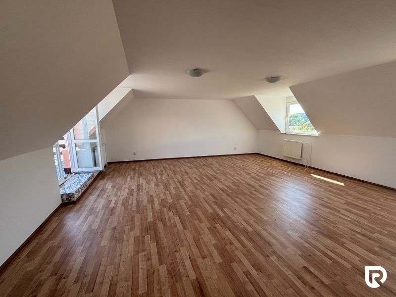 6-izbový rodinný dom s pozemkom 2218m2  | Horňany - Podkrovná izba v rodinnom dome s podlahou s dreveným dekorom a strešnými oknami.