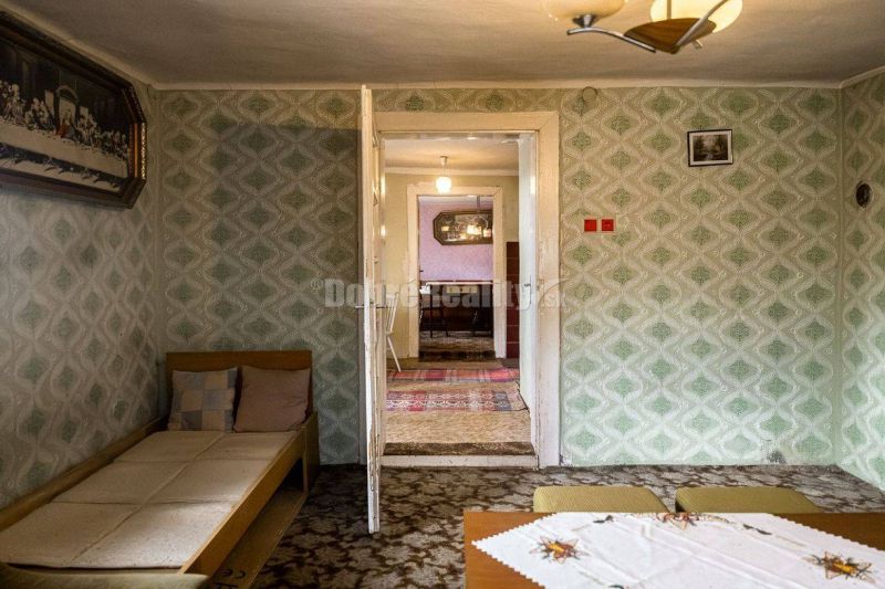 PREDAJ: Drevenica pri Ždiarskom potoku s príjemnou verandou, 135 m2, P - Izba v chate so vzorovanou tapetou, sedačkou a pohľadom do susednej miestnosti.