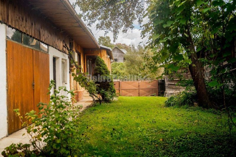 PREDAJ: Drevenica pri Ždiarskom potoku s príjemnou verandou, 135 m2, P - Záhrada pri chate v Polomke so zeleným trávnikom a drevenou bránou.