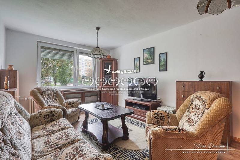 3-izbový byt v Šali na Vajanského ulici - Obývacia izba v 3-izbovom byte s pohovkou, kreslami a podlahou s dreveným dekorom.