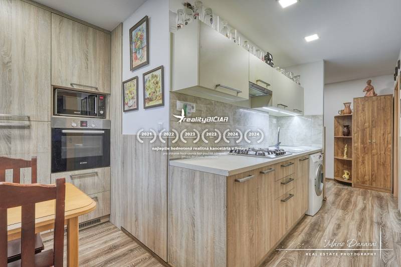 3-izbový byt v Šali na Vajanského ulici - Kuchyňa v 3-izbovom byte s indukčnou varnou doskou a podlahou s dreveným dekorom.