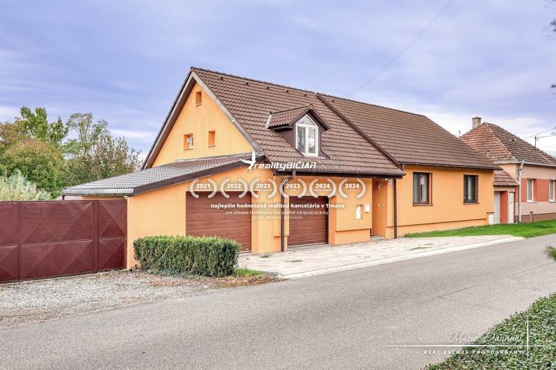 5-izbový rodinný dom s dvomi garážami v obci Špačince - Rodinný dom v Špačinciach na ulici Špačince s oranžovou fasádou a hnedou strechou.