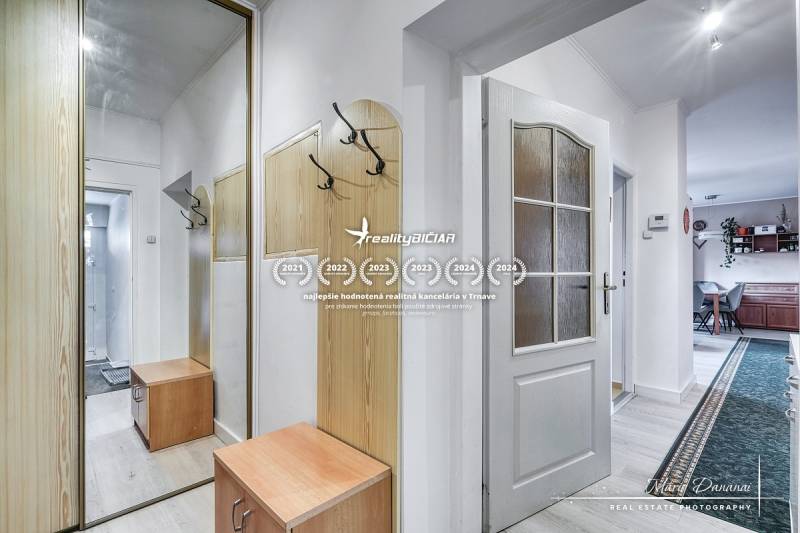 5-izbový rodinný dom s dvomi garážami v obci Špačince - Chodba s vešiakovou stenou a zrkadlom v rodinnom dome. Podlaha s dreveným dekorom.