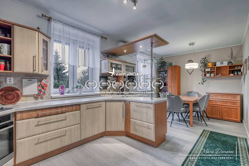 5-izbový rodinný dom s dvomi garážami v obci Špačince - Kuchyňa v rodinnom dome s podlahou s dreveným dekorom, vybavená kuchynským nábytkom.