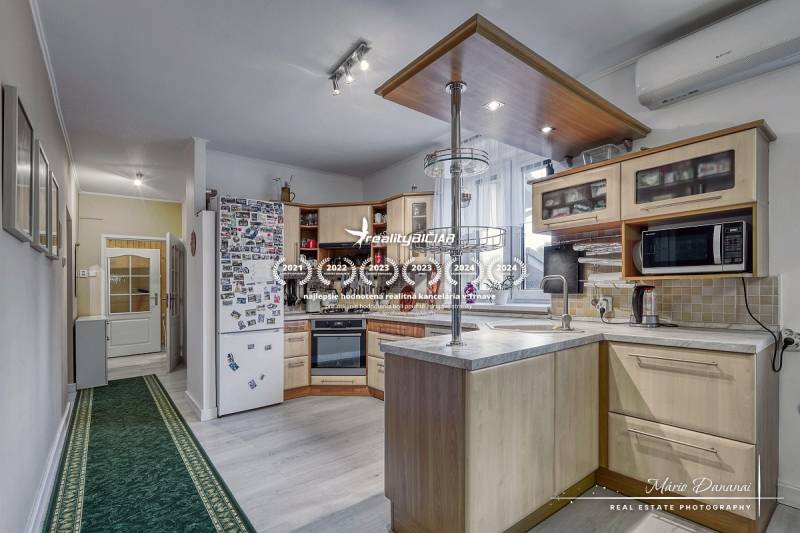 5-izbový rodinný dom s dvomi garážami v obci Špačince - Kuchyňa v rodinnom dome s podlahou s dreveným dekorom, spotrebiče a vybavenie.