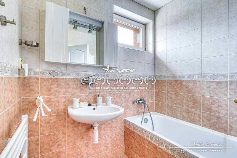 5-izbový rodinný dom s dvomi garážami v obci Špačince - Kúpeľňa v rodinnom dome s umývadlom, zrkadlom, vaňou a oknom nade dverami.