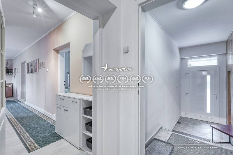 5-izbový rodinný dom s dvomi garážami v obci Špačince - Chodba v rodinnom dome s bielymi stenami a praktickým úložným priestorom.