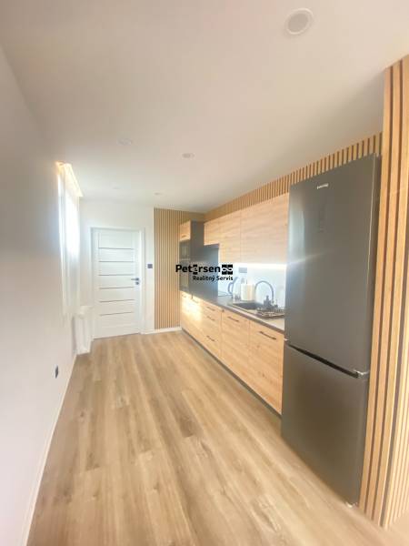 NA PRENÁJOM NOVOZREKONŠTRUOVANÝ 2-IZBOVÝ BYT, UL. ROŽŇAVSKÁ - Kuchyňa v 2-izbovom byte s podlahou s dreveným dekorom a svetlým nábytkom.