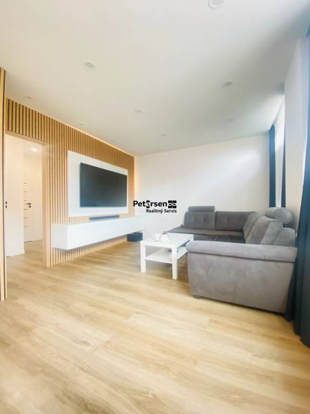 NA PRENÁJOM NOVOZREKONŠTRUOVANÝ 2-IZBOVÝ BYT, UL. ROŽŇAVSKÁ - Obývacia izba v 2-izbovom byte s pohovkou a podlahou s dreveným dekorom.