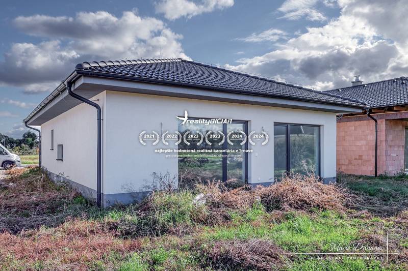 Novostavba 4-izbového rodinného domu v obci Slov.Nová Ves - Rodinný dom na predmestí Slovenskej Novej Vsi so záhradou a bielou fasádou.