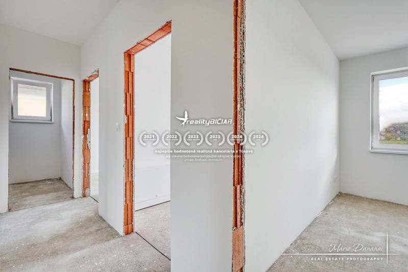 Novostavba 4-izbového rodinného domu v obci Slov.Nová Ves - Interiér rodinného domu s bielymi stenami a drevenými rámami dverí bez podlahovej krytiny.