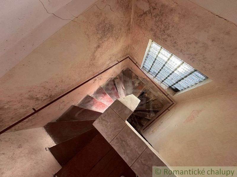 Starý dom s dušou – čaká na nový život v jednej z najkrajších ulíc Nov - Schodisko v rodinnom dome s veľkým oknom a opotrebovanými stenami.
