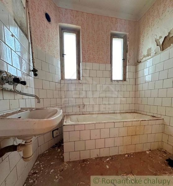 Starý dom s dušou – čaká na nový život v jednej z najkrajších ulíc Nov - Kúpeľňa v rodinnom dome s oprýskanými stenami a starou vaňou.