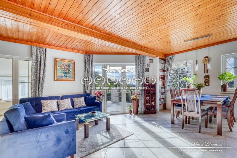 7-izbový rodinný dom s úžasným výhľadom v prestížnej lokalite Devín - Obývacia izba v chate s dreveným stropom, modrou sedačkou a jedálenským stolom.
