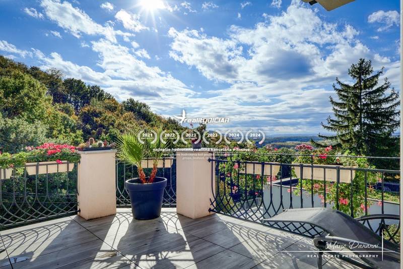 7-izbový rodinný dom s úžasným výhľadom v prestížnej lokalite Devín - Balkón rodinného domu v Bratislave - Devíne s výhľadom na les a kvetinová výzdoba.