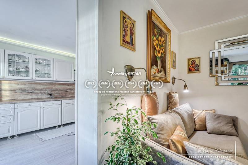 7-izbový rodinný dom s úžasným výhľadom v prestížnej lokalite Devín - Interiér rodinného domu s bielou kuchynskou linkou a útulným kútikom s pohovkou a dekoráciami.
