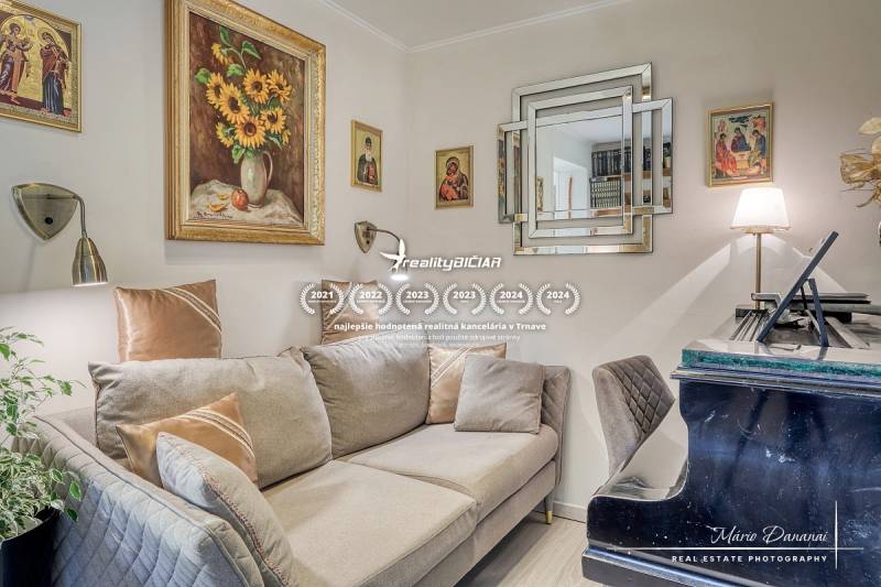 7-izbový rodinný dom s úžasným výhľadom v prestížnej lokalite Devín - Obývacia izba s pohovkou, klavírom a obrazmi v rodinnom dome.